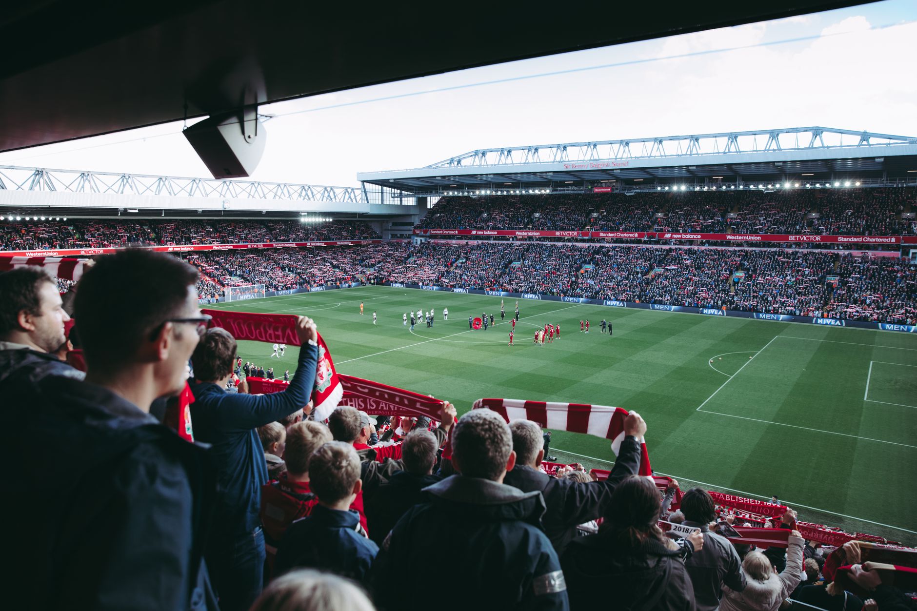 Auswärtsfans mit Schals feiern im Gästeblock eines englischen Fußballstadions
